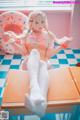 A woman in a pink and white outfit sitting on a table.