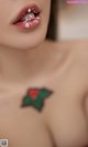 A close up of a woman with a holly tattoo on her chest.