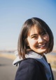 A woman with a smile on her face standing on a beach.