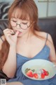 A woman sitting on a couch eating a bowl of strawberries.