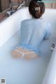 A woman in a blue shirt is sitting in a bathtub.