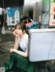 A woman sitting on the ground next to a sign.