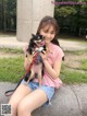 A woman sitting on a bench holding a small dog.