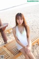 A woman sitting on a wooden bench on the beach.